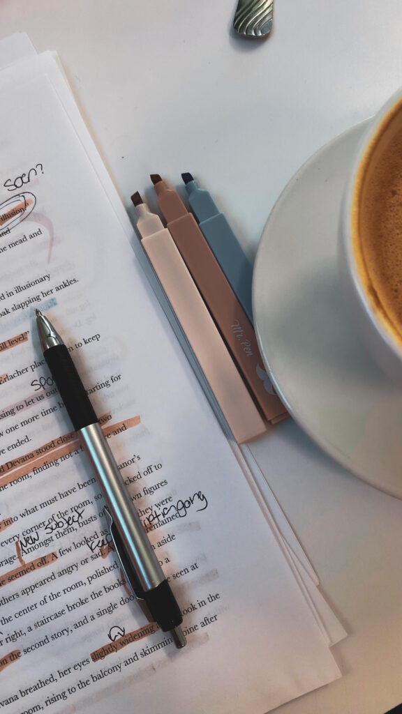 desk with notes, a pen and three highlighters