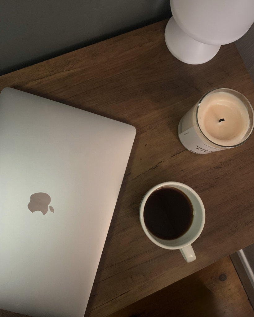 Desk with computer close, coffee and a candel